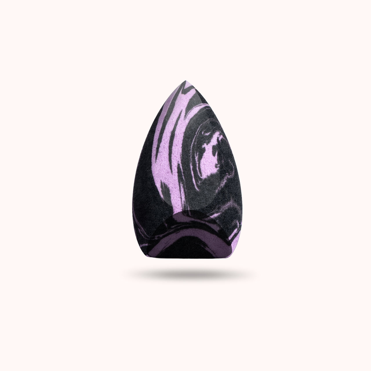 A teardrop-shaped makeup sponge with a black and purple marbled pattern, centered on a light cream background with a soft drop shadow.
