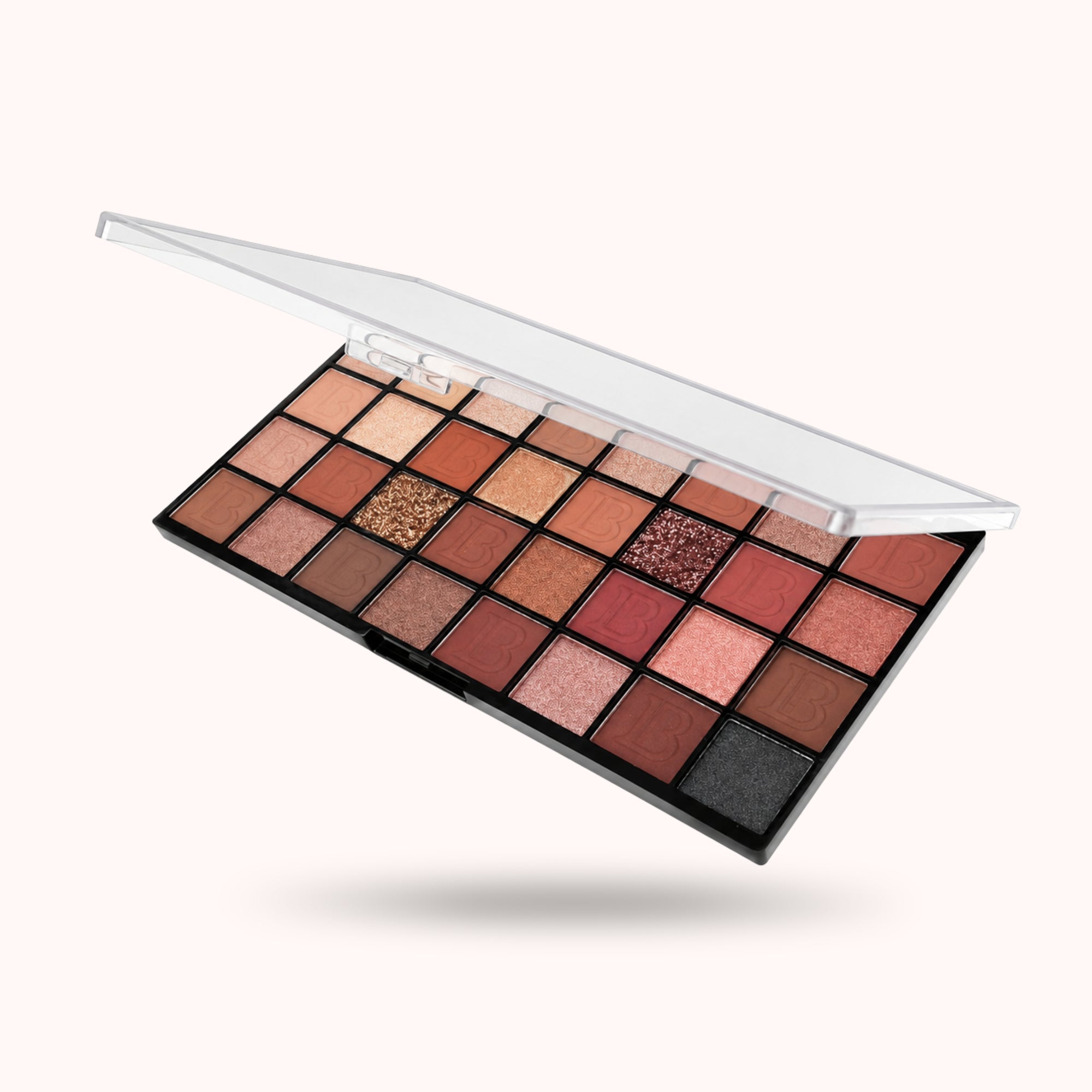 A 24-shade eyeshadow palette with an open clear lid, floating diagonally against a solid off-white background. The shades range from warm neutrals and browns to pinks, reds, and a dark charcoal.