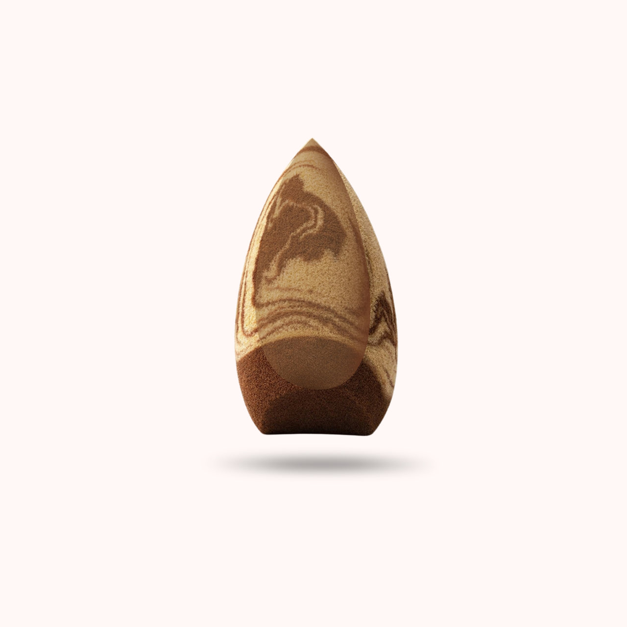 A teardrop-shaped makeup sponge with a marbled wood-grain pattern in shades of brown and beige, shown against a solid off-white background with a soft drop shadow.